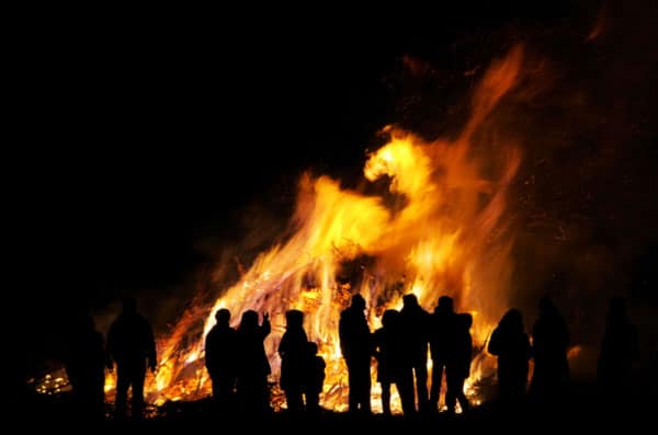 The silhouette of people celebrating can be seen in front of a huge bonfire on bonfire night